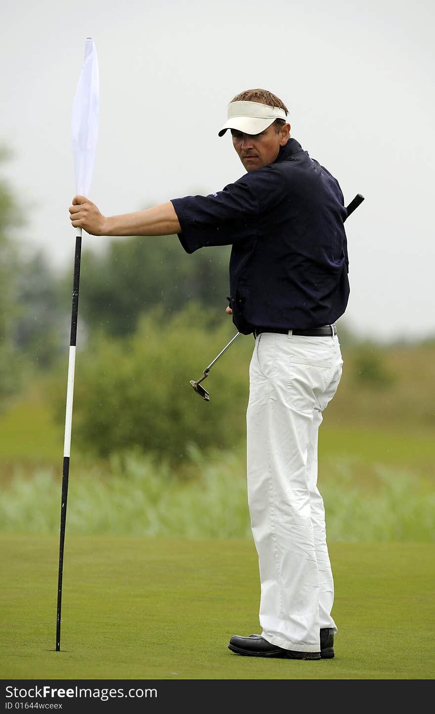 Golfer remove a hole flag before final shot. Golfer remove a hole flag before final shot