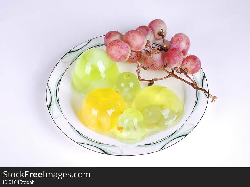 Jelly and a branch of grape in dish on white background. Jelly and a branch of grape in dish on white background