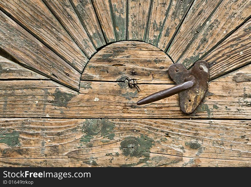 Detail of a door with a handle and sun ornament. Detail of a door with a handle and sun ornament