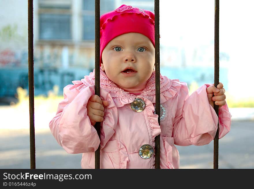 Little girl behind old railing (grille).