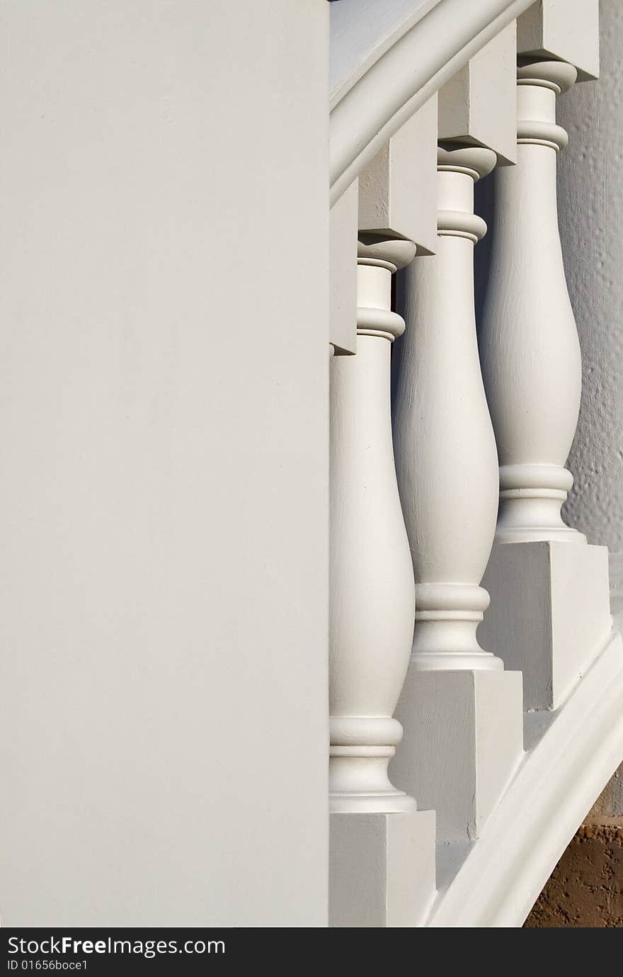 White, large, columns on a banister with negative space on the left. White, large, columns on a banister with negative space on the left.