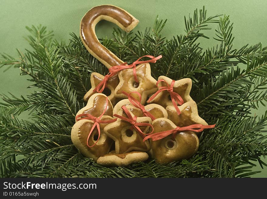 A pile of gingerbread cookies nestled in nest of fir branches and isolated on green paper. A pile of gingerbread cookies nestled in nest of fir branches and isolated on green paper