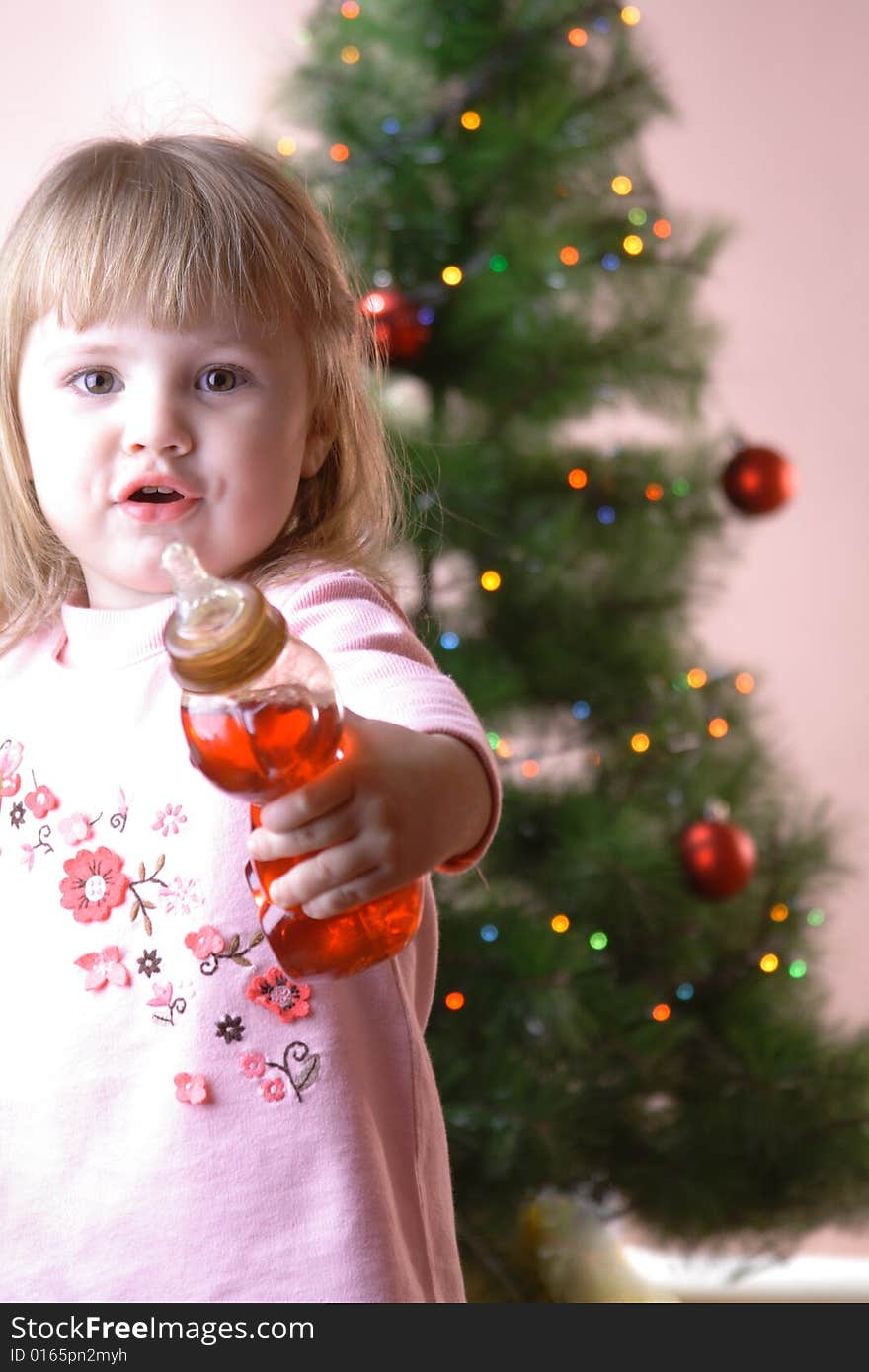 Baby with bottle near christmas tree