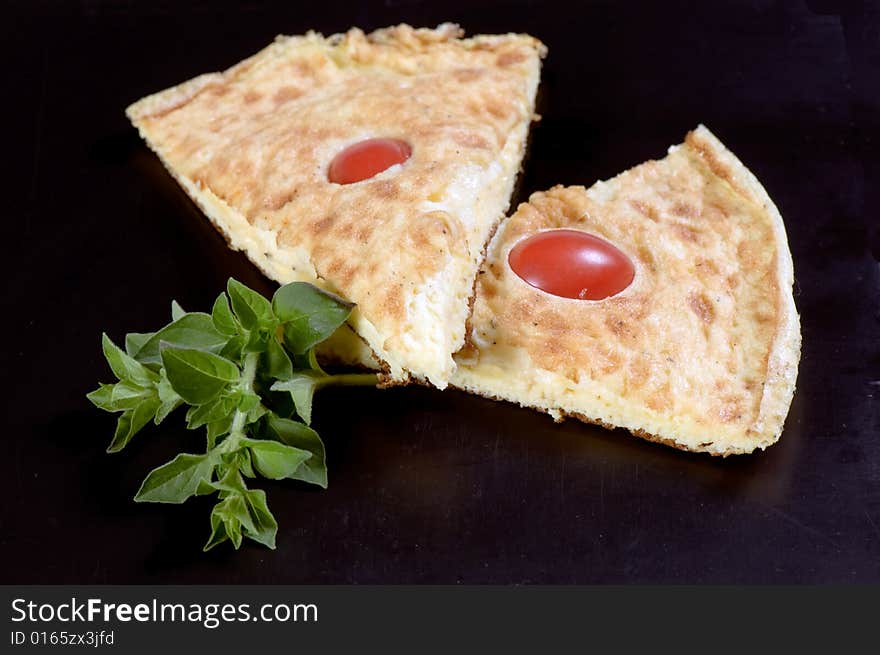 Slices of Frittata omelet made with eggs, potato and onion and garnished with cherry tomatoes and herbs. Slices of Frittata omelet made with eggs, potato and onion and garnished with cherry tomatoes and herbs