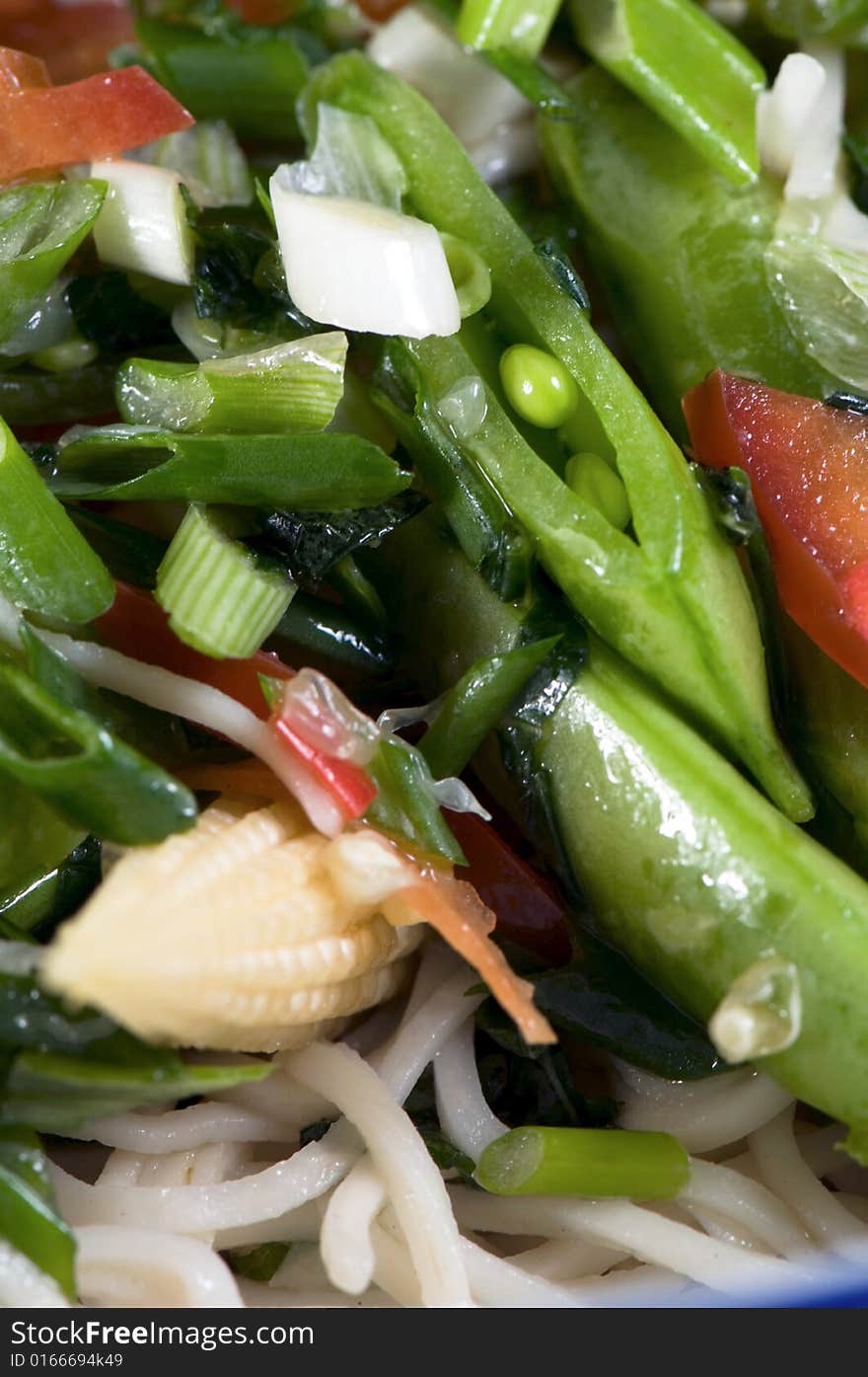 A macro up of rice noodle relish with rice noodles baby corn red peppers bean sprouts chopped mint and spring onions dressed with sesame oil, sugar lime juice and soy sauce. Decorated with ornamental chopsticks. A macro up of rice noodle relish with rice noodles baby corn red peppers bean sprouts chopped mint and spring onions dressed with sesame oil, sugar lime juice and soy sauce. Decorated with ornamental chopsticks