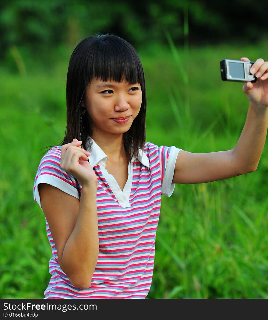 A girl taking a photo of herself with a handphone camera. A girl taking a photo of herself with a handphone camera.