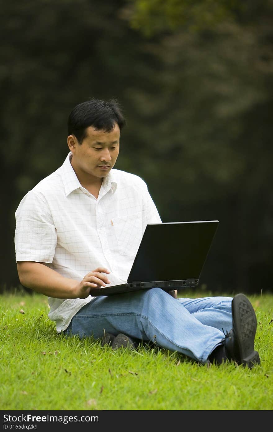 A young man using a laptop outdoors