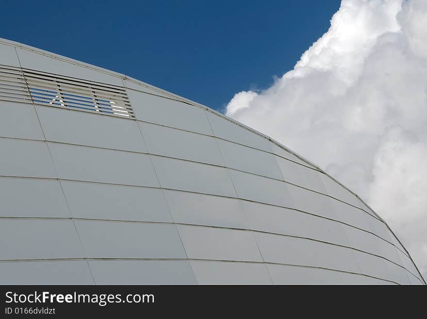 Detail of a curved building against cloudy sky. Detail of a curved building against cloudy sky