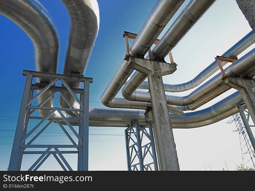 Industrial pipelines on pipe-bridge against blue sky.