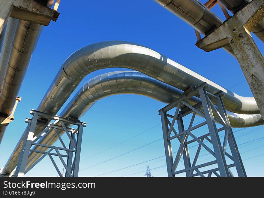 Industrial pipelines on pipe-bridge against blue sky.