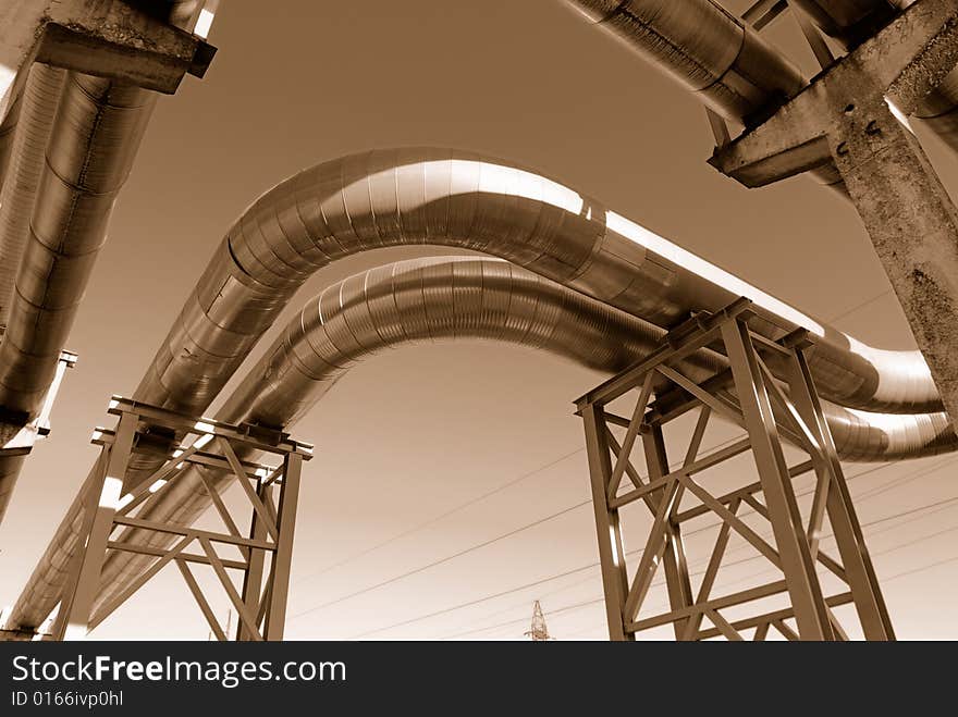 Industrial pipelines on pipe-bridge against blue sky.