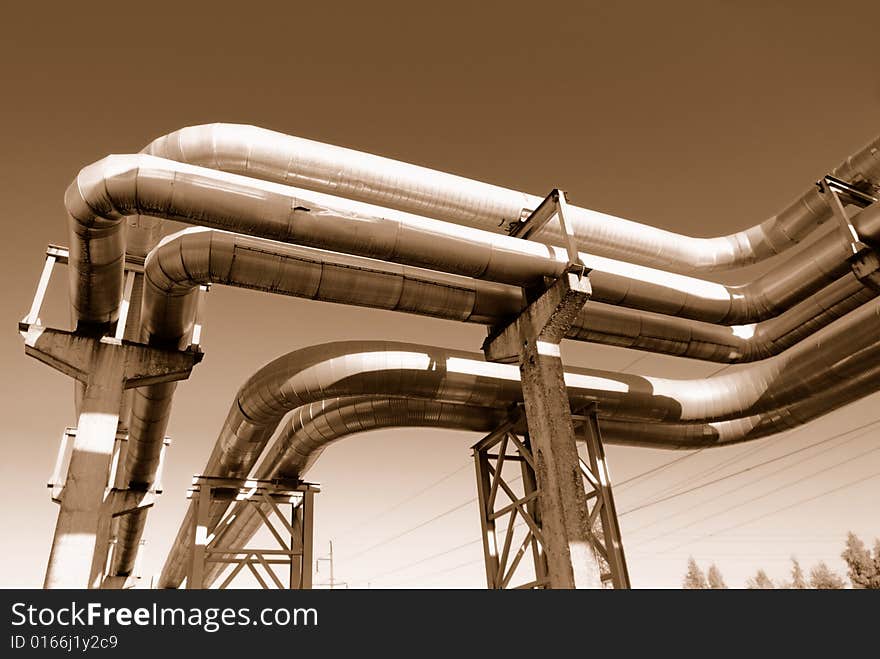 Industrial pipelines on pipe-bridge against blue sky.