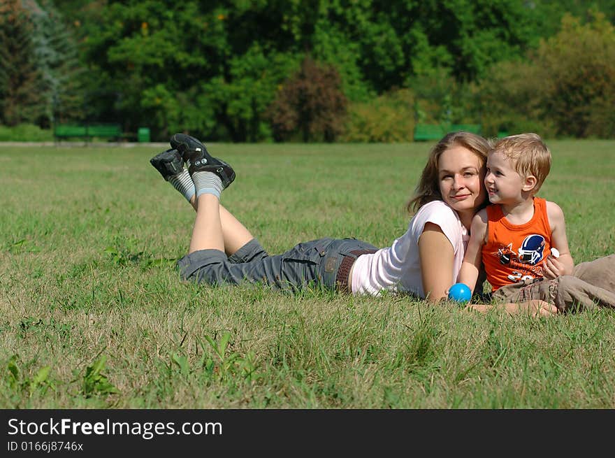 Mother and son are lying on the grass