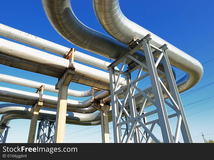 Industrial pipelines on pipe-bridge against blue sky.