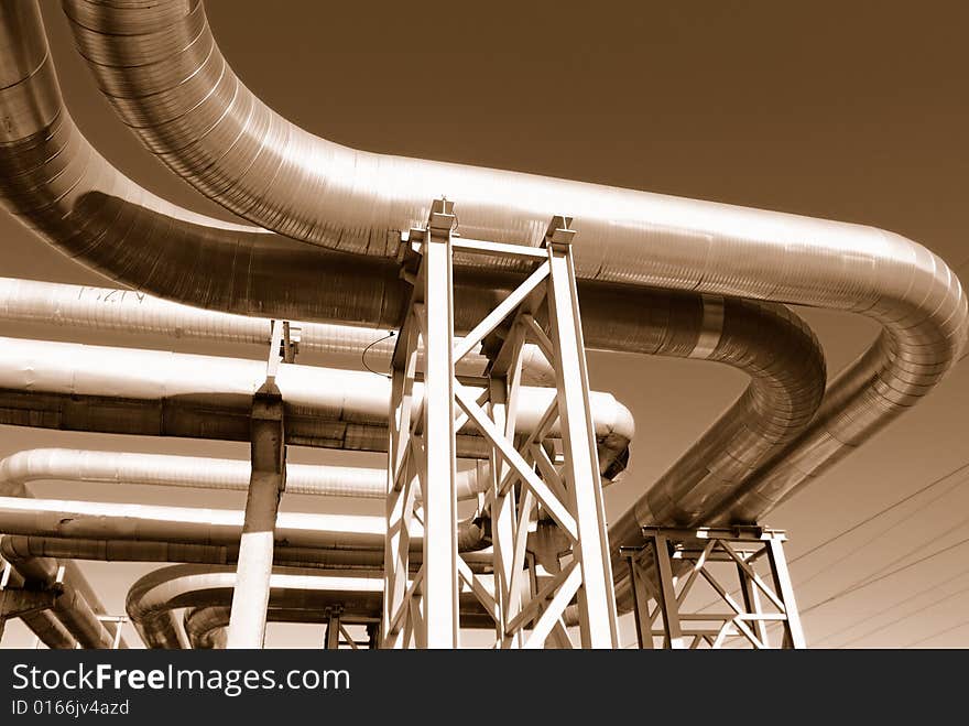 Industrial pipelines on pipe-bridge against blue sky.