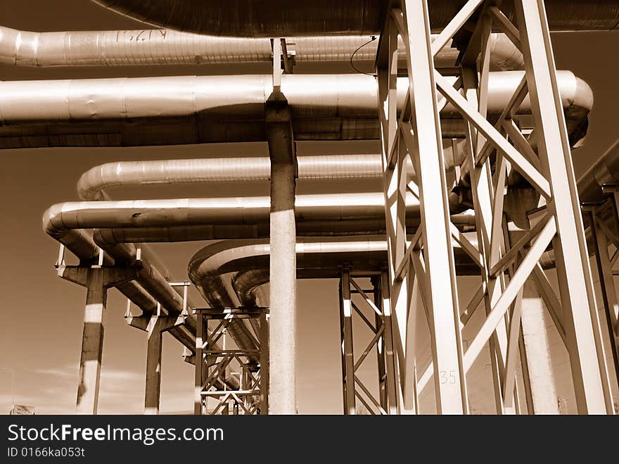 Industrial pipelines on pipe-bridge against blue sky.