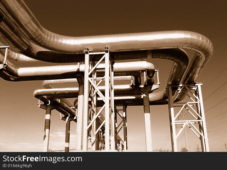 Industrial pipelines on pipe-bridge against blue sky.