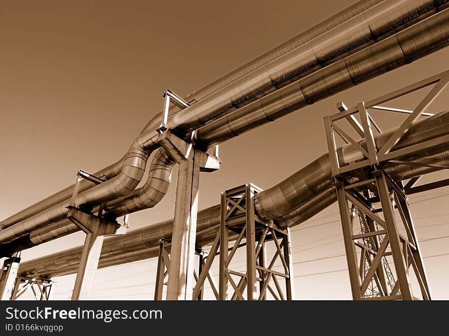 Industrial pipelines on pipe-bridge against blue sky.