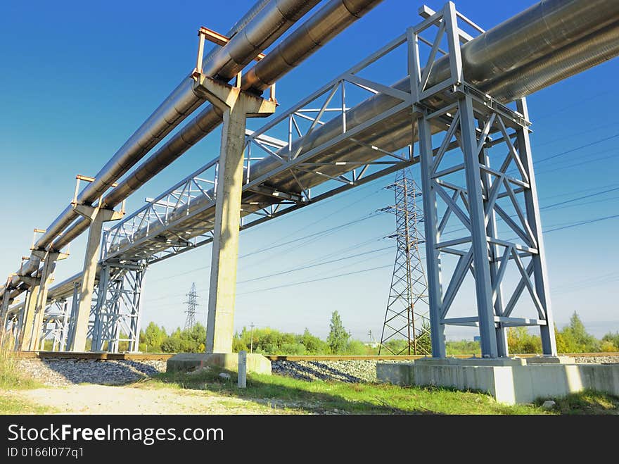 Industrial pipelines on pipe-bridge against blue sky.