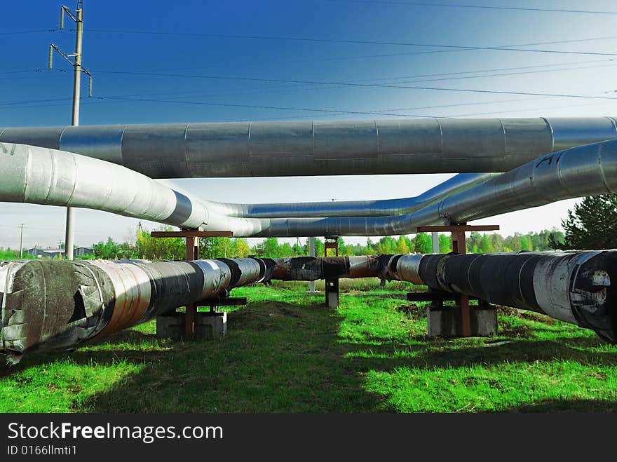 Industrial pipelines on pipe-bridge against blue sky.