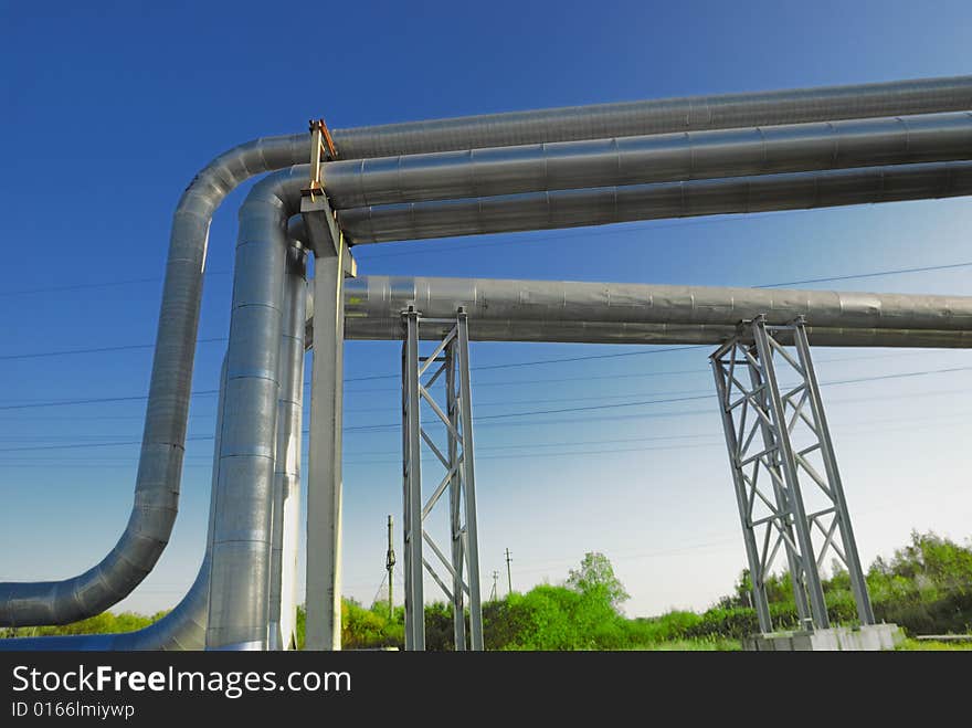 Industrial pipelines on pipe-bridge against blue sky.