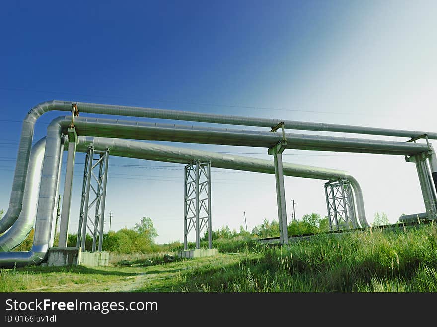 Industrial pipelines on pipe-bridge against blue sky.