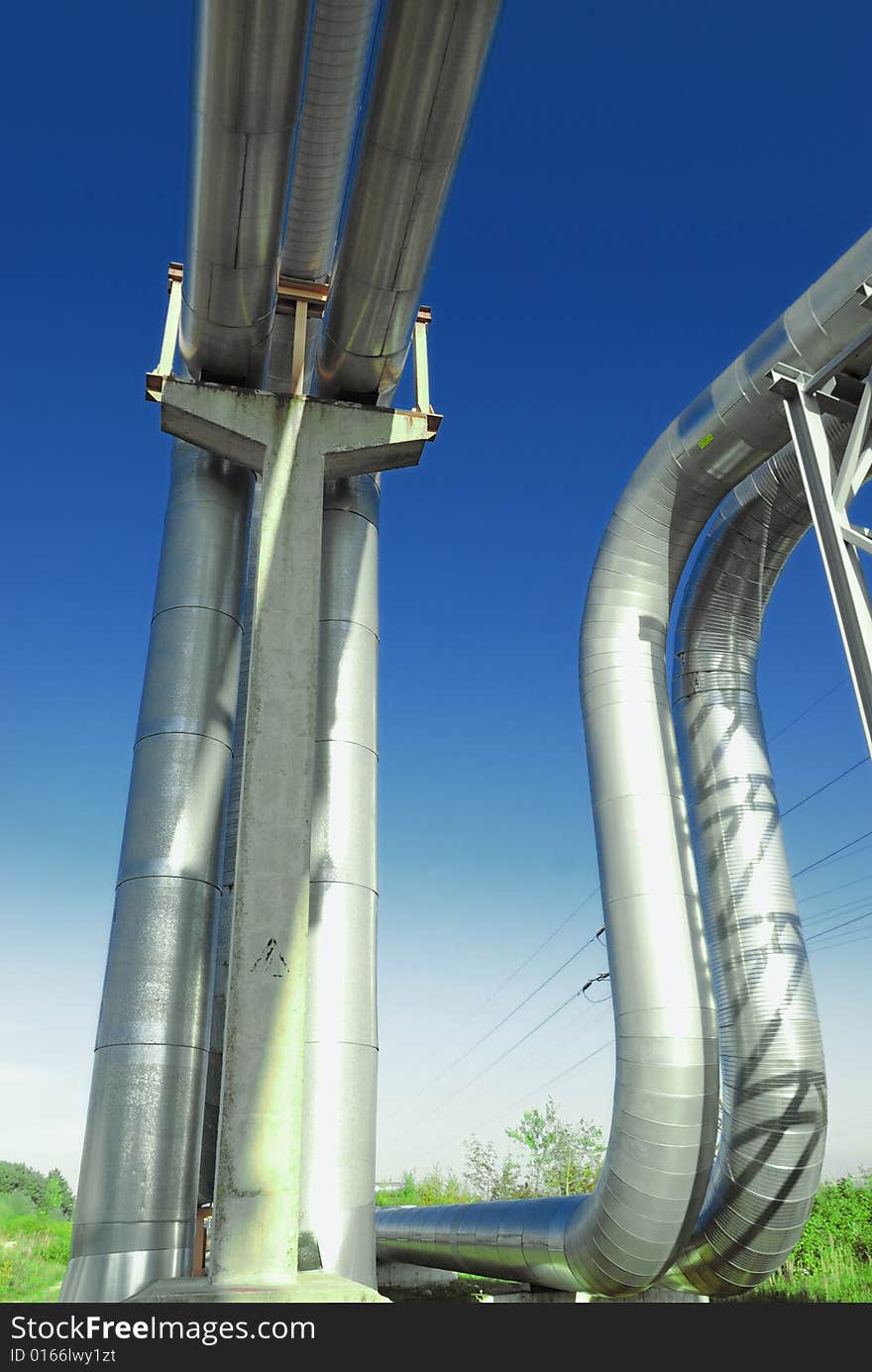 Industrial pipelines on pipe-bridge against blue sky.