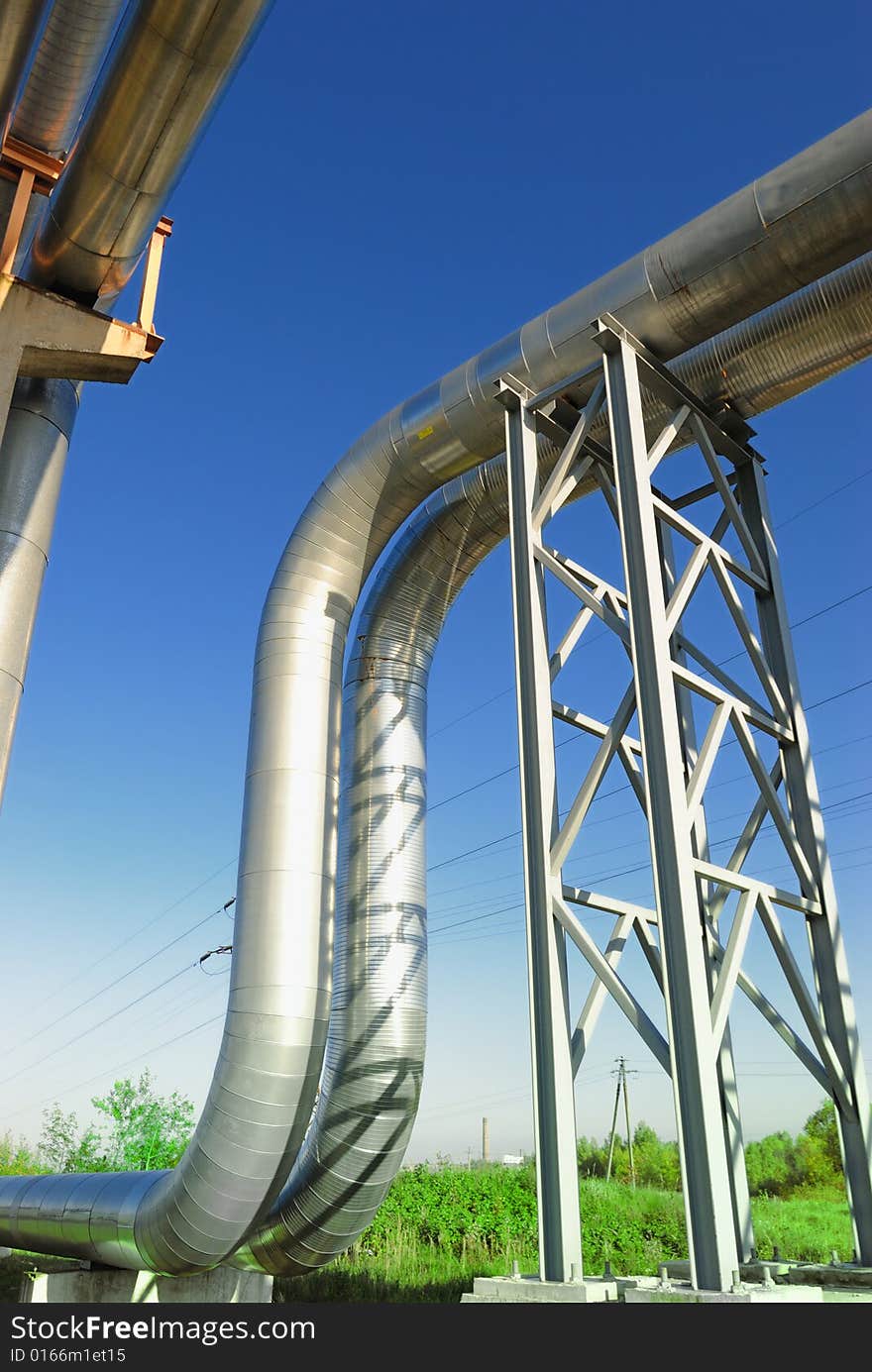 Industrial pipelines on pipe-bridge against blue sky.