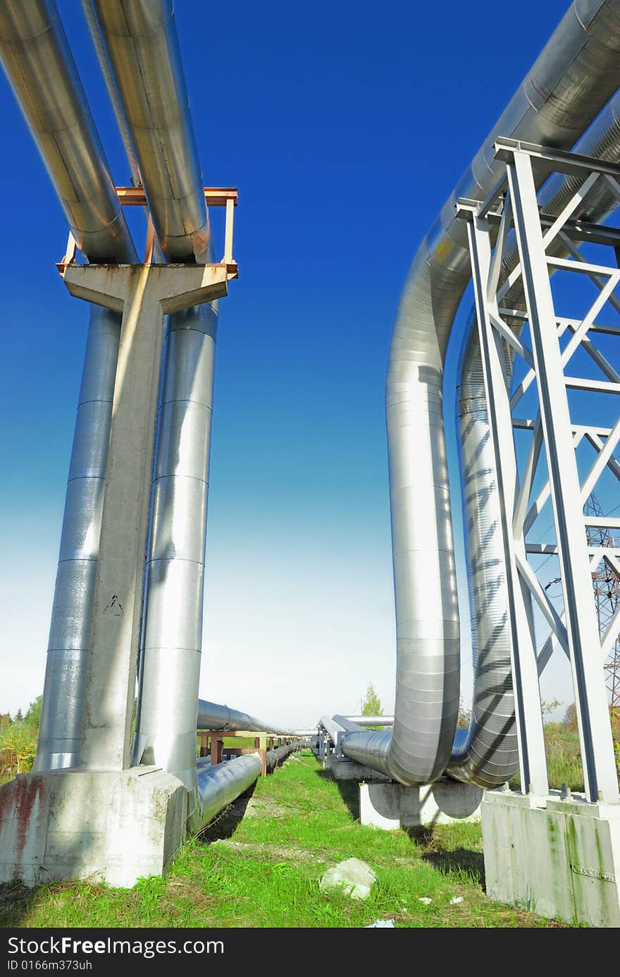 Industrial pipelines on pipe-bridge against blue sky.