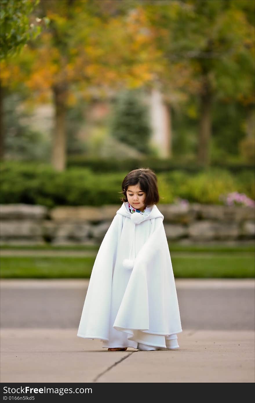 Little girl in white cape outdoors. Little girl in white cape outdoors