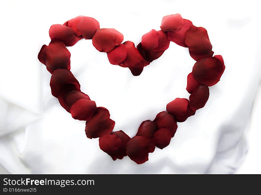 Symbol of heart from rose-petals on white silk