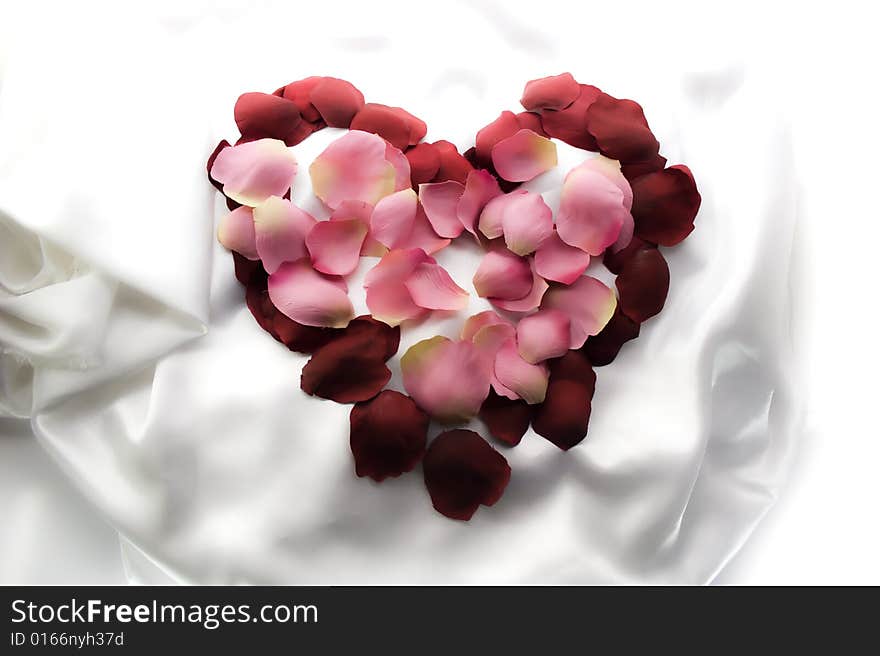 Symbol of heart from rose-petals on white silk