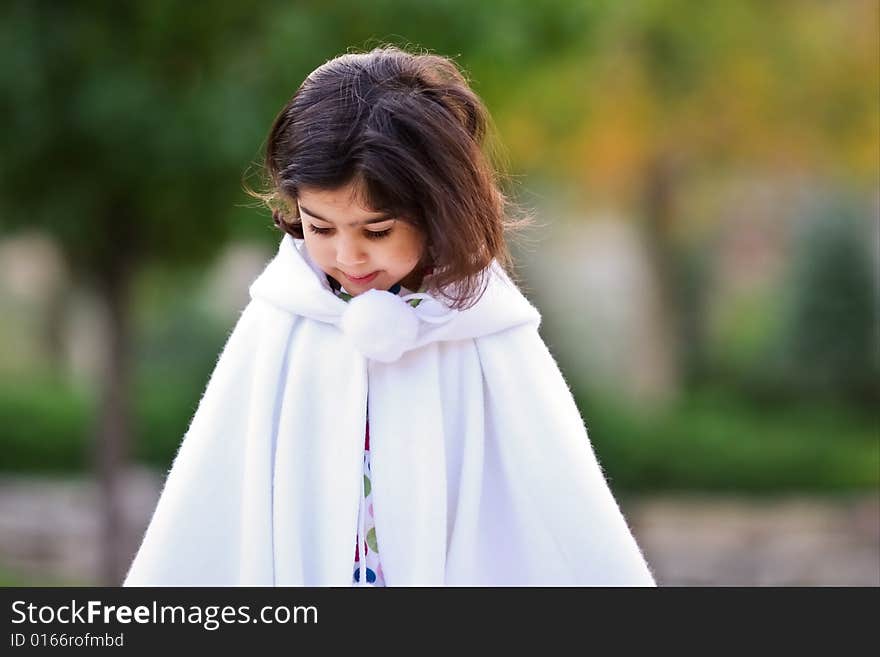 Little girl in white cape outdoors. Little girl in white cape outdoors