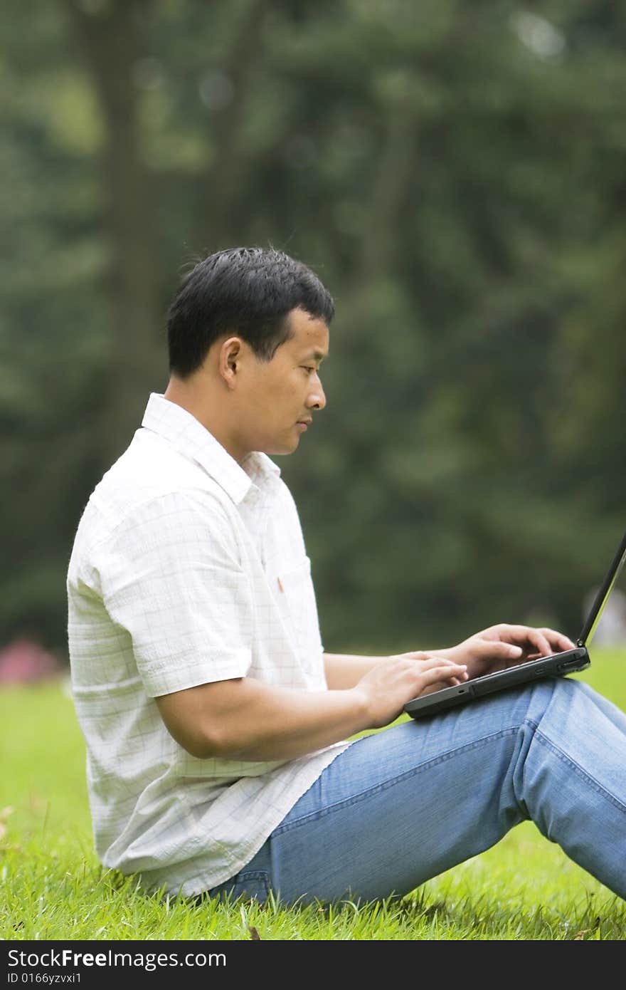 A young man using a laptop outdoors