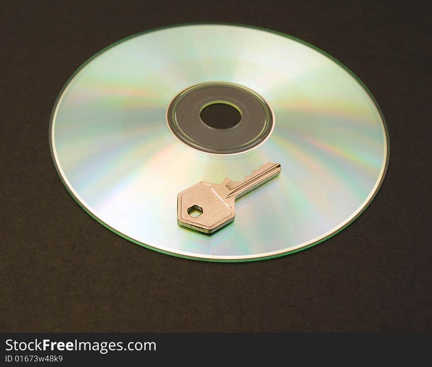 Photograph of a CD with small metal key. Dark background. Photograph of a CD with small metal key. Dark background.