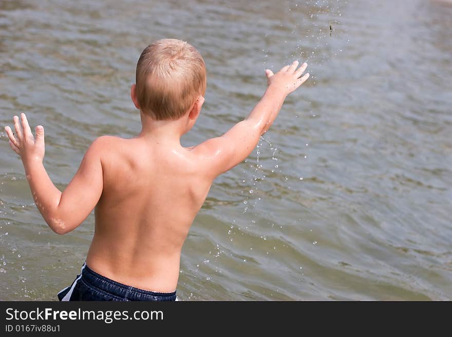 Boy throwing sand in the water. Boy throwing sand in the water