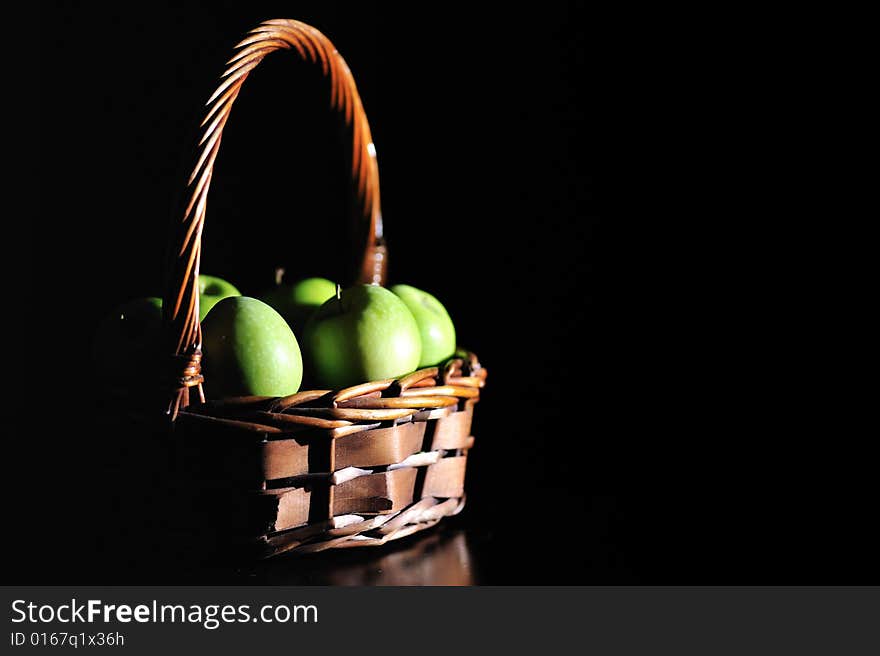 A wooden basket filled with green apples. A wooden basket filled with green apples