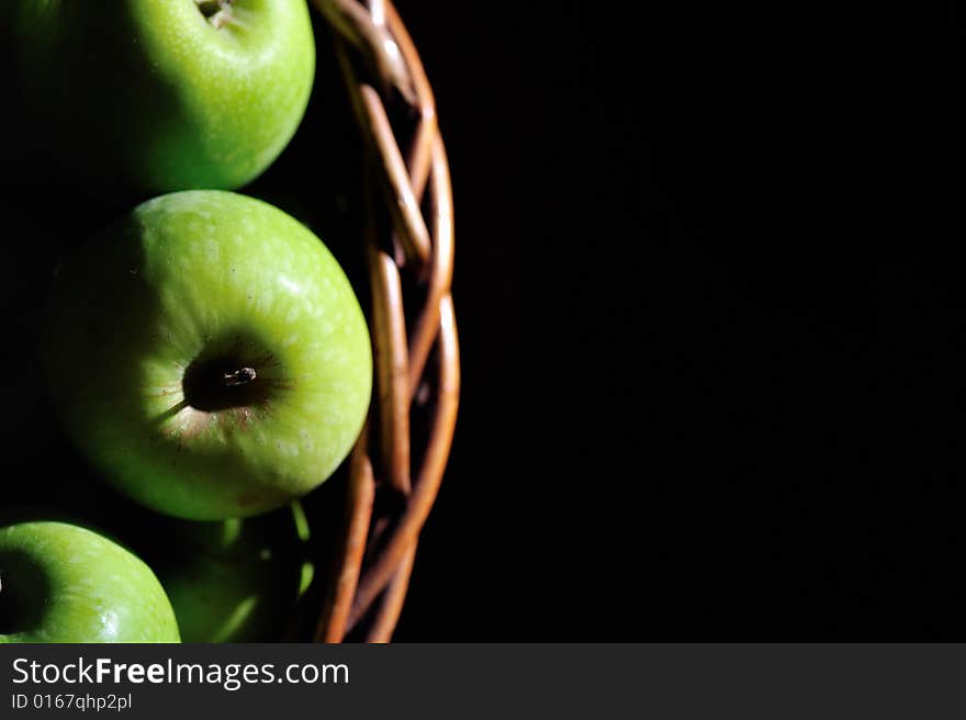 A wooden basket filled with green apples. A wooden basket filled with green apples