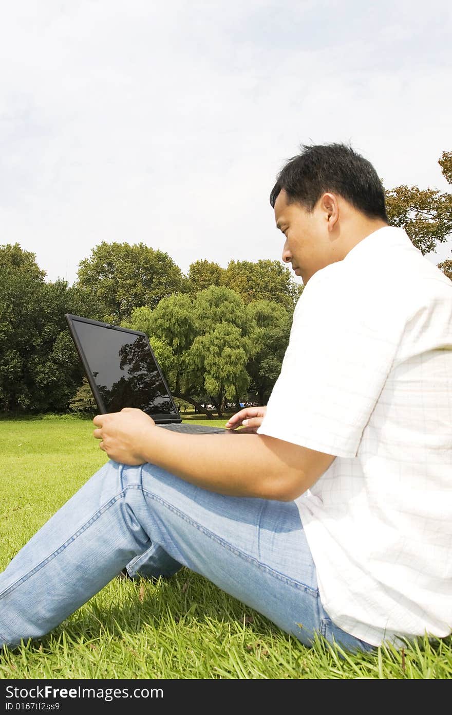 A young man using a laptop outdoors