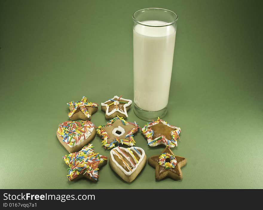 Christmas cookies and a glass of milk isolated against green paper. Christmas cookies and a glass of milk isolated against green paper