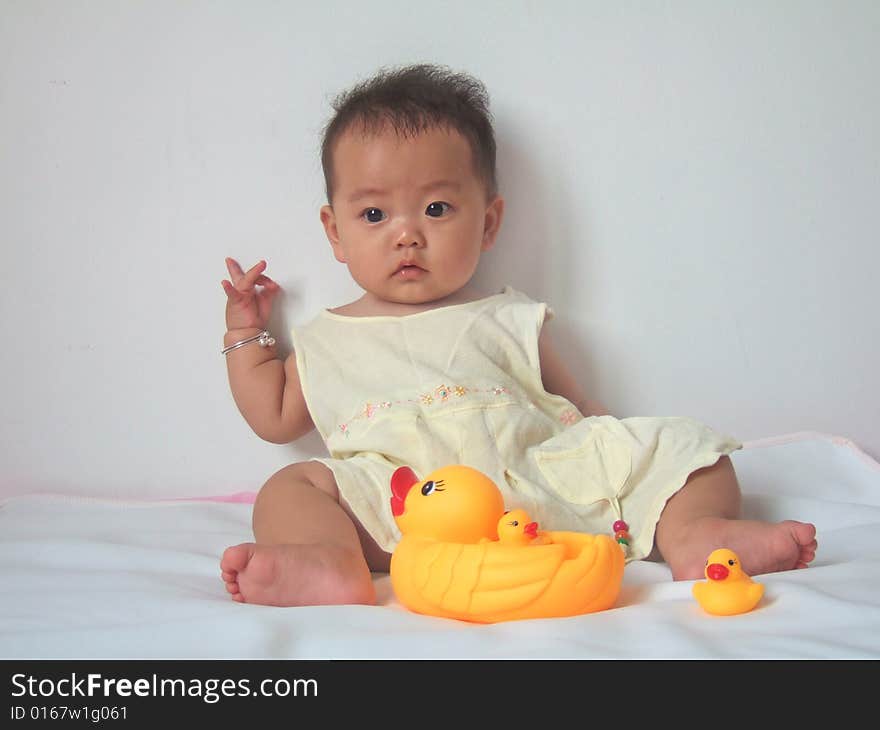 Pretty baby and toy ducks on a bed