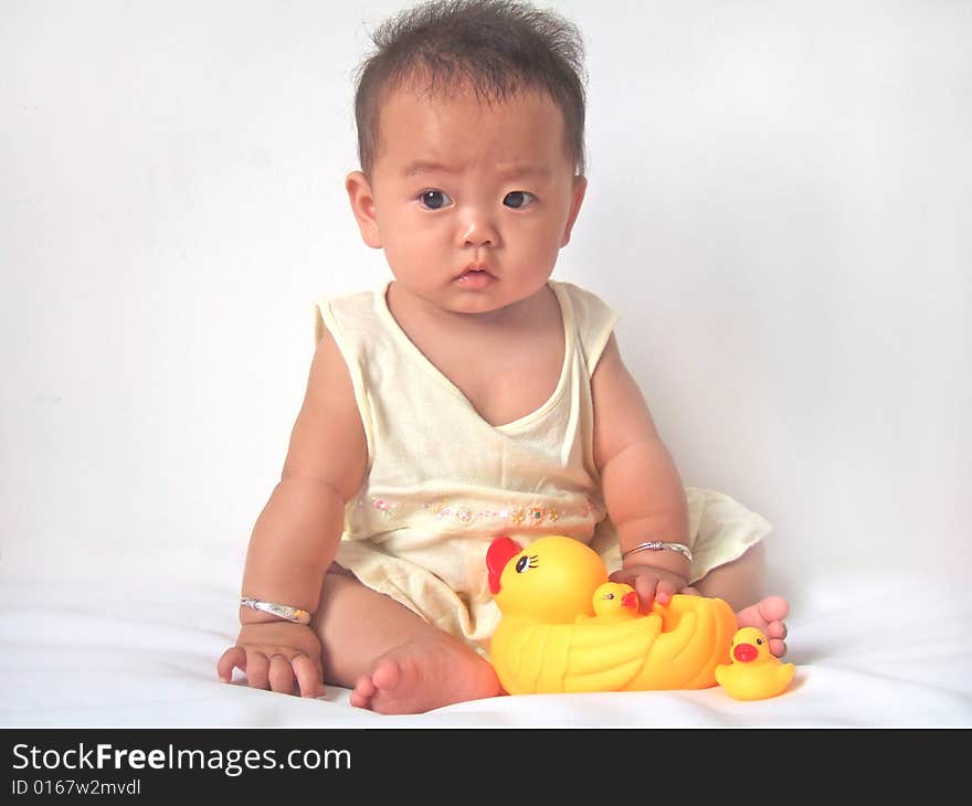 Pretty baby and toy ducks on a bed