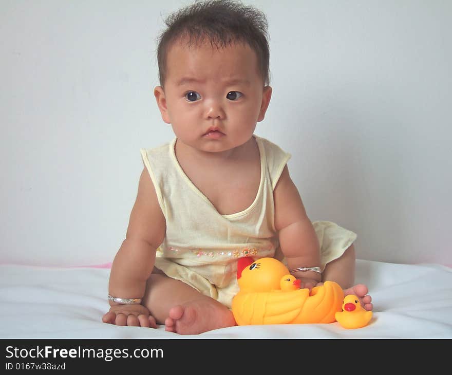 Pretty baby and toy ducks on a bed