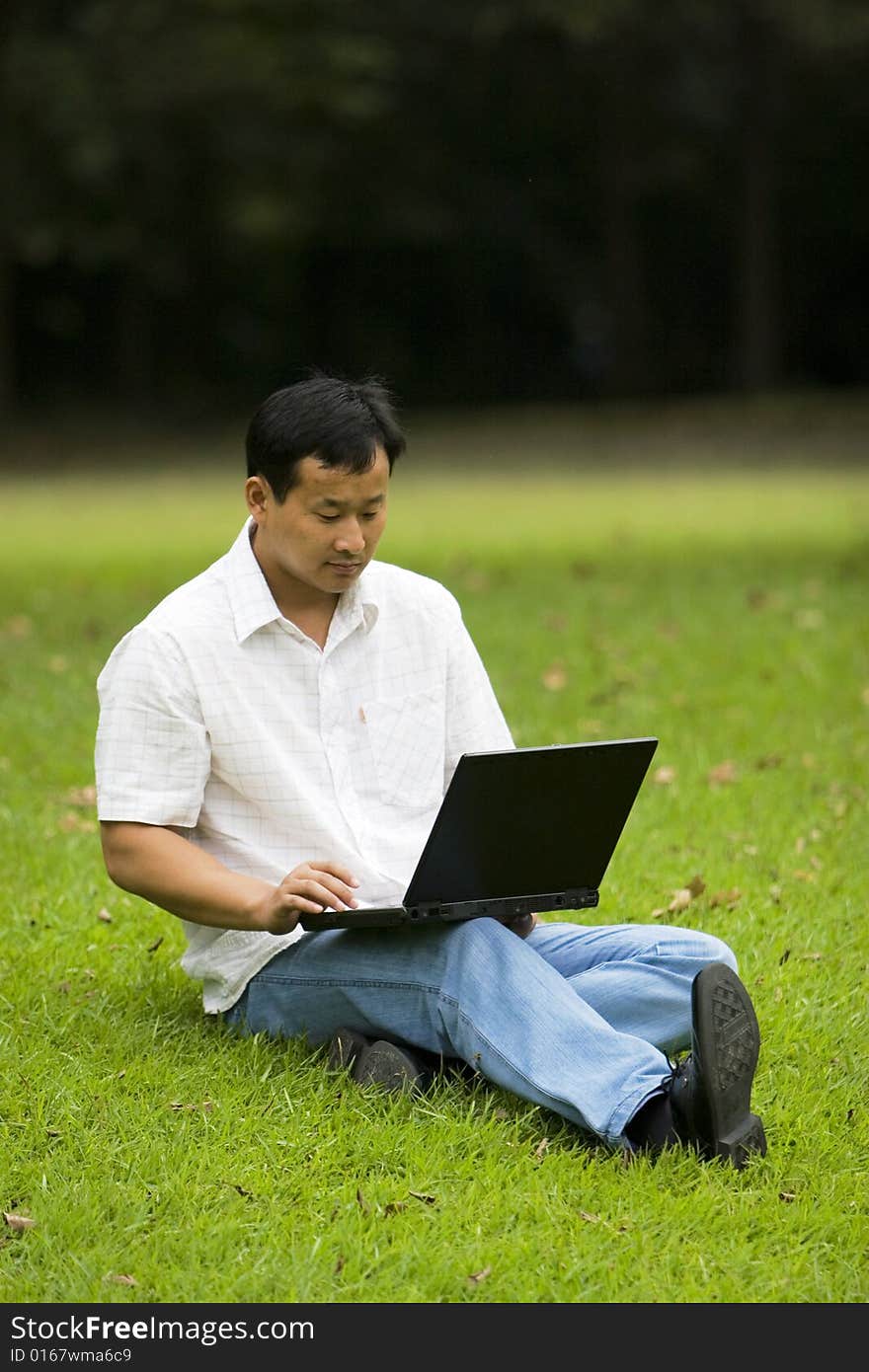 A young man using a laptop outdoors