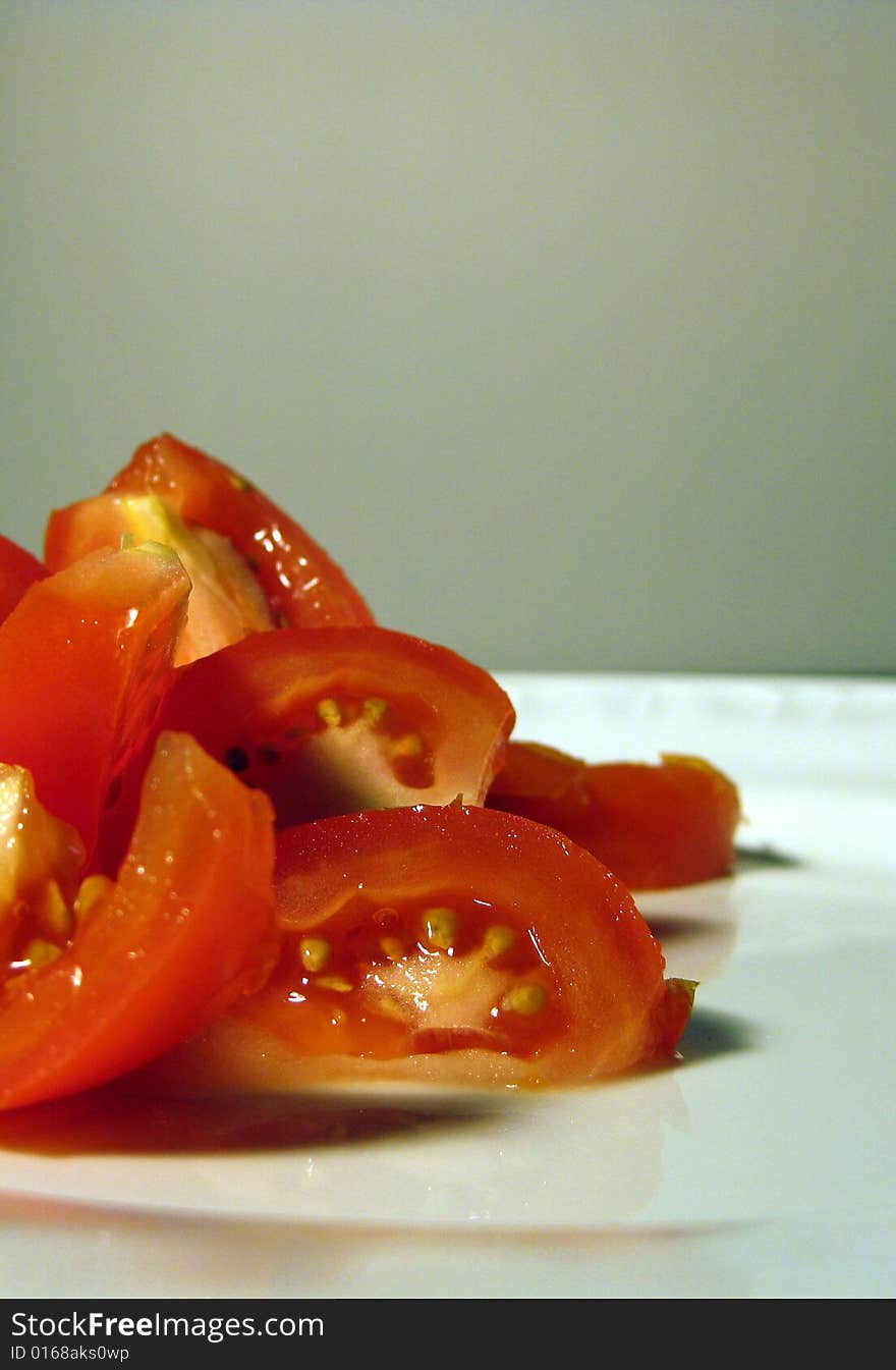 Red cut on quarters tomato on white plate. Red cut on quarters tomato on white plate.