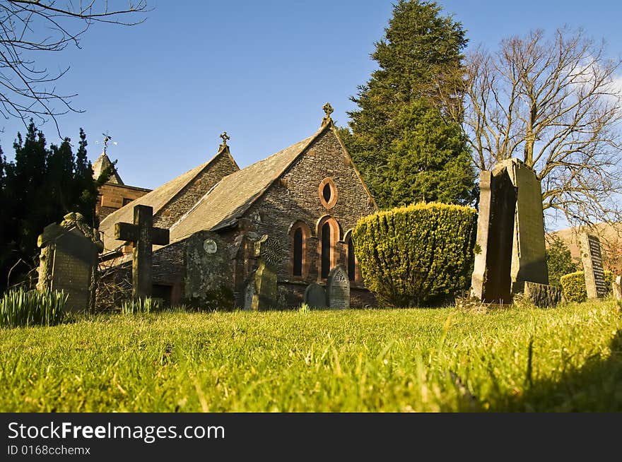 Village church and cemetery taken from a low view point under a bright blue sky. Village church and cemetery taken from a low view point under a bright blue sky.