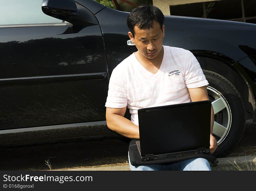 The man working outdoors with a laptop.