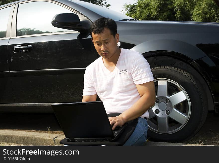 The man working outdoors with a laptop.