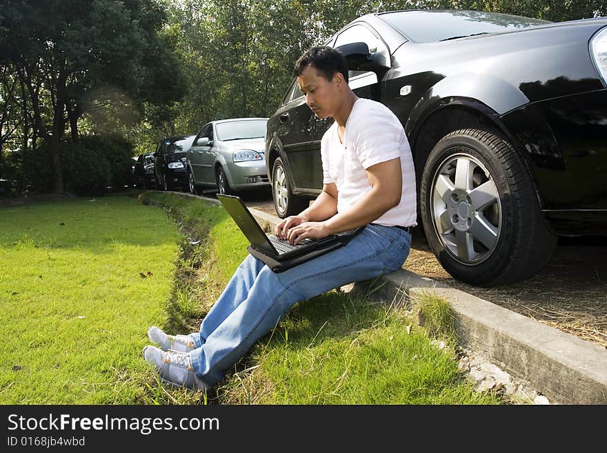 The man working outdoors with a laptop.