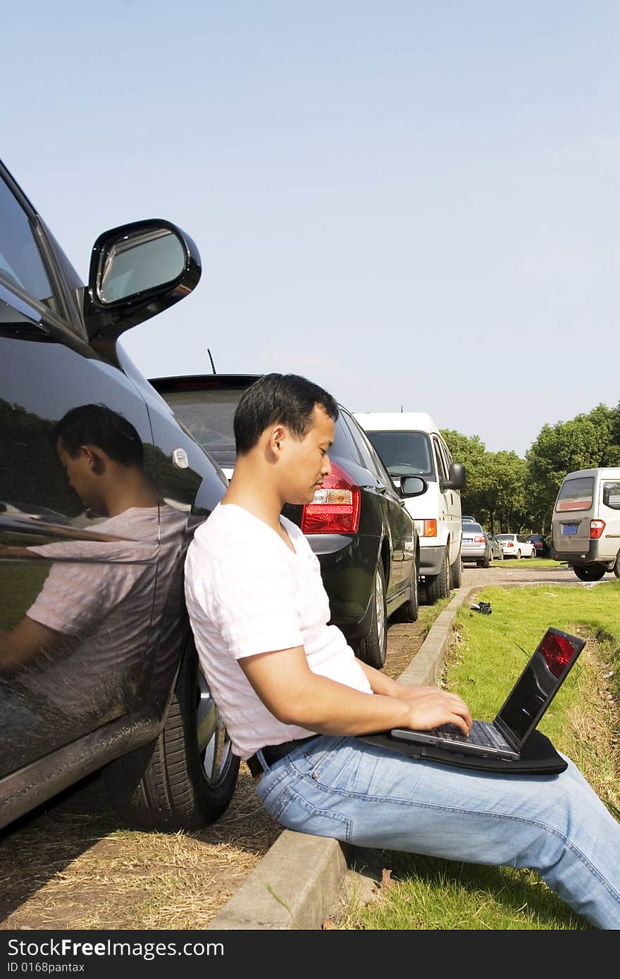 The man working outdoors with a laptop.